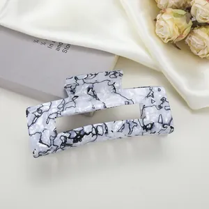 Vue détaillée d'une grande pince à cheveux rectangulaire avec motif marbre noir et blanc