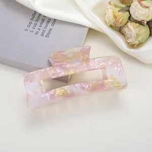 Dettaglio della molletta quadrata in acetato con motivo marmorizzato rosa su raso beige