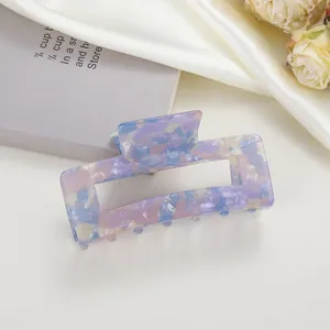 Detailed close-up of a medium acetate claw clip with marble texture on silk fabric
