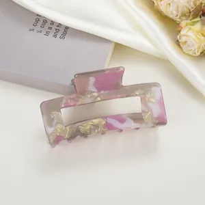 Detail of 8cm marble acetate hair claw clip on silk fabric with elegant floral pattern