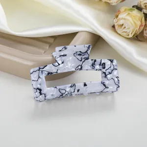 Detalle de una pinza para el pelo rectangular de acetato jaspeado negro y blanco en seda