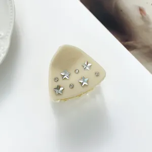 Close-up of cream star hair claw clip with rhinestones on a white aesthetic background