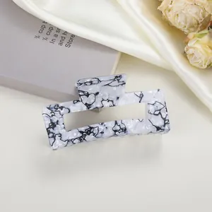 Detail view of large rectangular hair claw with black and white marble ink patterns