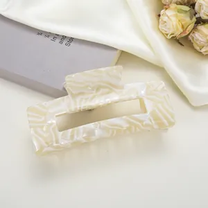 Détail d'une pince à cheveux rectangulaire effet marbre crème sur un fond de soie élégant