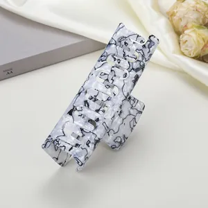 Détail d'une pince à cheveux motif marbre noir et blanc sur tissu en soie