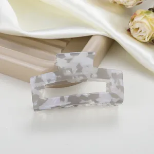 Pinza de pelo rectangular de acetato jaspeado sobre un fondo de seda blanca suave