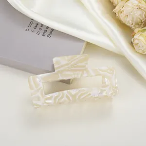 Macro detail of rectangle acetate hair claw clip with creamy marble pattern