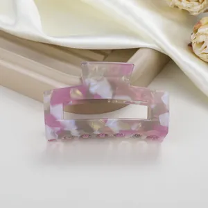 Primer plano de pinza de pelo en acetato jaspeado rosa y blanco sobre una bandeja
