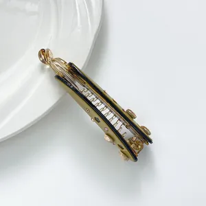 Pince banane à cheveux avec strass et acétate présentée sur une assiette en céramique
