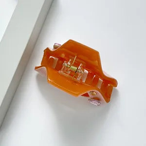 Orangefarbene Haarklammer aus Acetat mit bunten Strasssteinen und goldener Metallfeder