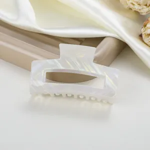Detalle de la pinza de pelo de acetato marmoleado blanco con diseño hueco y brillo irisado