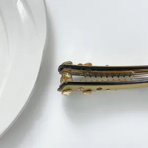 Détail de la pince à cheveux banane en acétate avec strass colorés et dents antidérapantes