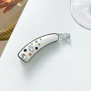 Vue détaillée d'une pince banane avec fleurs en strass et accents vert émeraude