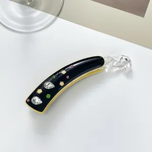 Détail de la pince banane avec strass colorés et motif trèfle ajouré sur base noire