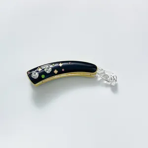 Detail of banana hair clip featuring rhinestones and hollow clover patterns on acetate