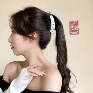 White acetate banana clip with crystals and black clover motifs on high ponytail
