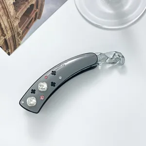 Detail of grey acetate banana clip with sparkling square rhinestones and clover pattern