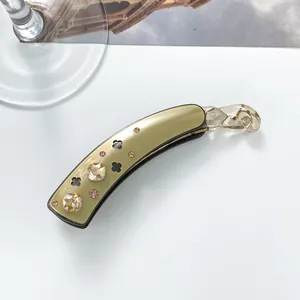 Macro view of olive gold banana clip featuring amber rhinestones and clover hollow design