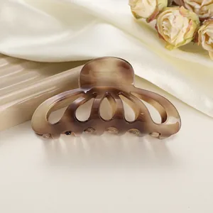 Dettaglio della pinza per capelli in acetato tartarugato su tessuto di seta beige