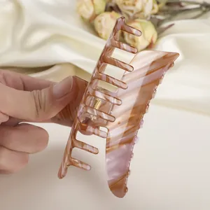 Detalle de una pinza para el pelo grande de acetato con textura de ámbar en la mano
