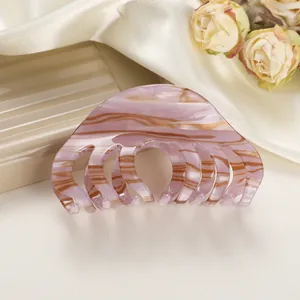 Detail van roze en bruine marmerpatroon haarklem op beige satijnen achtergrond