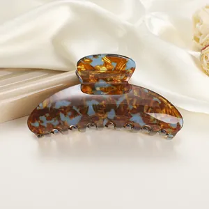 Detail of large acetate hair claw clip featuring brown and blue marble texture on silk