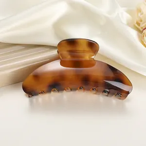 Detailed view of large leopard tortoiseshell hair claw clip on soft silk fabric