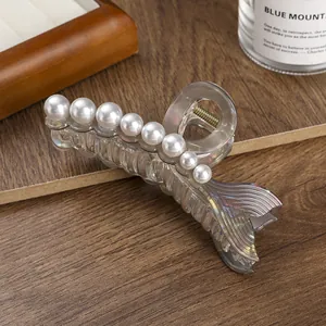 Iridescent mermaid tail hair claw clip with pearls on a dark wood background