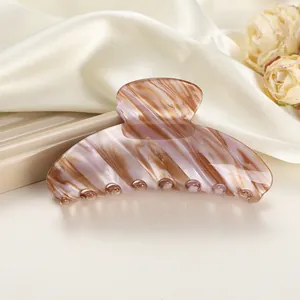 Detailed close-up of a large marbled leopard print hair claw clip on silk fabric