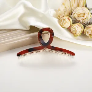 Close-up of a tortoiseshell claw clip with gold spring on elegant silk fabric background