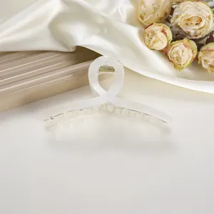 Detail of large white marble texture hair claw clip with cross design on silk background