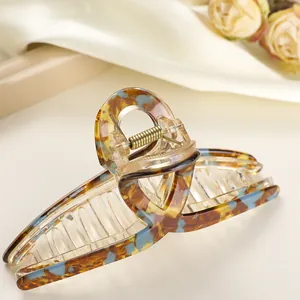 Close-up of a tortoiseshell hair claw clip with amber and blue resin texture and gold spring