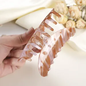 Large pink marble leopard print hair claw clip held by hand on silk background