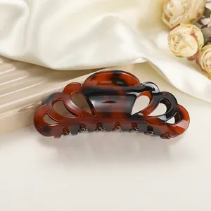Detail of elegant leopard print hair claw clip on silk background with tortoiseshell texture