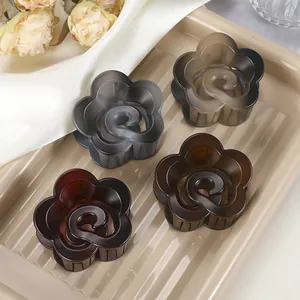 Détail de pinces à cheveux en forme de fleur en résine ambre, grise et rouge mat