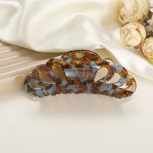 Macro detail of tortoiseshell acetate hair claw clip on silk fabric with dried flowers