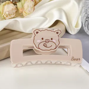 Détail d'une pince à cheveux ours beige en acrylique avec texte Bear sur soie blanche