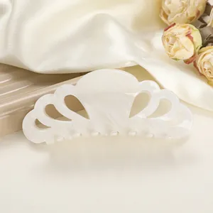 Macro view of cream white marble acetate hair claw with hollow petal design and glossy finish