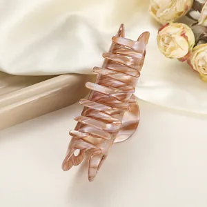 Detailed view of elegant large marbled claw clip on silk background with dried roses