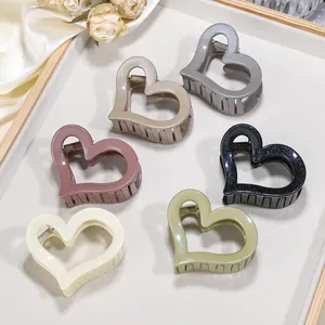 Dettaglio di pinze per capelli a forma di cuore glitterate in sei colori su seta elegante
