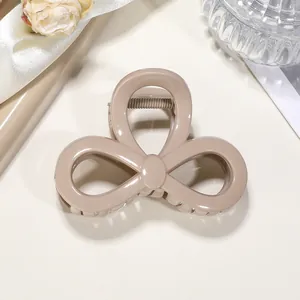 Detail of khaki flower-shaped hair claw clip on soft fabric background with macro texture