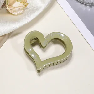 Dettaglio di un fermaglio per capelli a cuore verde con glitter su tessuto di seta