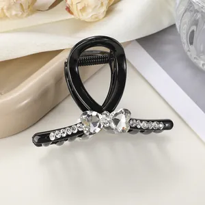 Detalle de pinza para el pelo negra con pedrería de corazón sobre tela elegante