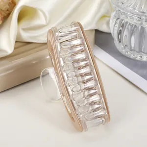 Detail view of a large acrylic hair claw clip with beige edges on a silk fabric background