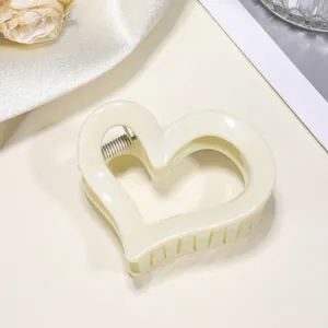 Dettaglio dell'elegante pinza per capelli a cuore color crema con glitter su seta