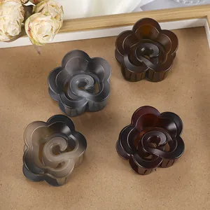 Détail de quatre pinces à cheveux fleur mate aux tons ambre et marron sur plateau