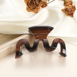 Close-up of wavy tortoise shell hair claw clip with amber gradient on white velvet