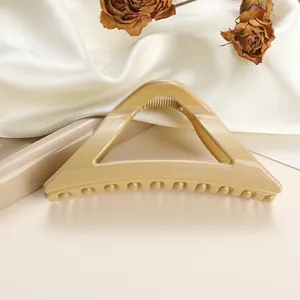 Detail of a geometric triangle hair claw clip in cream beige on elegant silk fabric