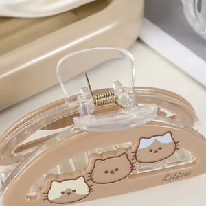Detail of a beige acrylic hair claw clip featuring cute kitten patterns and metal spring
