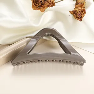 Detail of a large hollow triangle hair claw clip in dark grey on white silk background